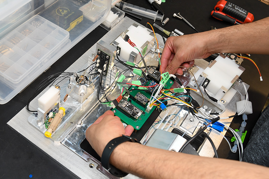close-up photo of hands working on a circuit board on top of a metal plate