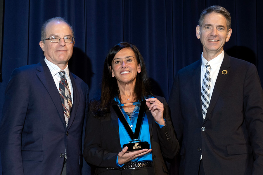 Todd Citron (left) and Bill Crossley (right) stand with Grazia Vittadini as she holds the commemorative gift she received for giving this year's Boeing Distinguished Lecture