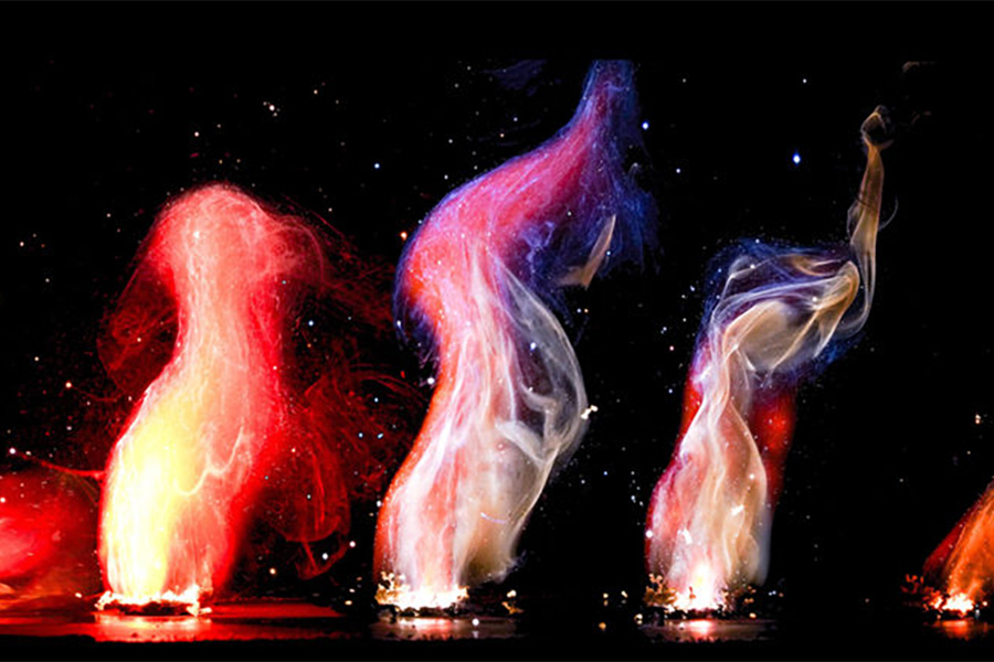 small test samples of rocket propellant burning, and producing colorful plumes of smoke