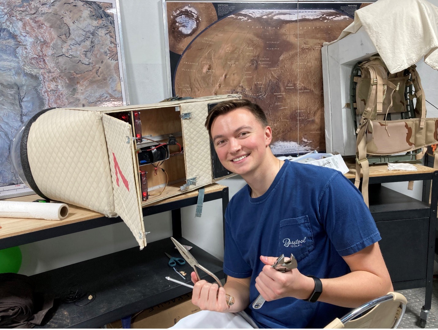 Mason tinkering with a malfunctioning EVA suit in the lower deck of the main habitat