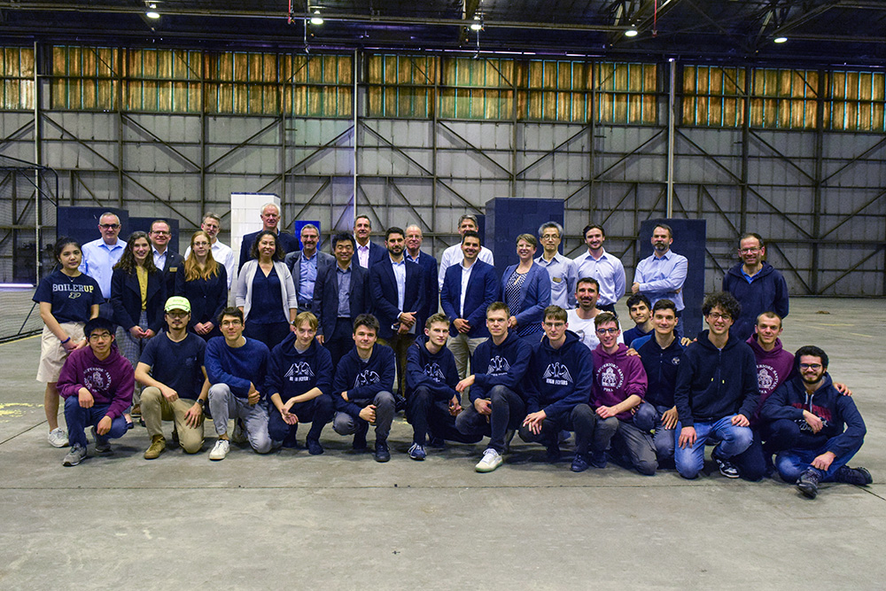 Large group of people posed for a photo inside an aircraft hangar