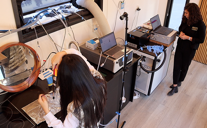 Purdue civil engineering PhD student and researcher Jinglin Jiang conducts her hair care routine while Nusrat Jung, assistant professor of civil engineering, observes data inputs during hair care routine emissions experiments conducted in the Purdue zero Energy Design Guidance for Engineers (zEDGE) Tiny House.