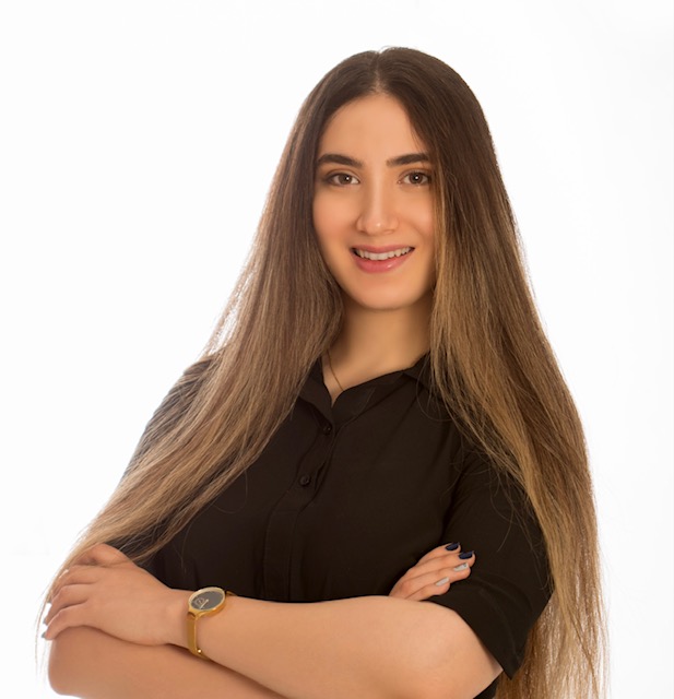 A person with long hair wearing a black shirt and folded armsDescription automatically generated