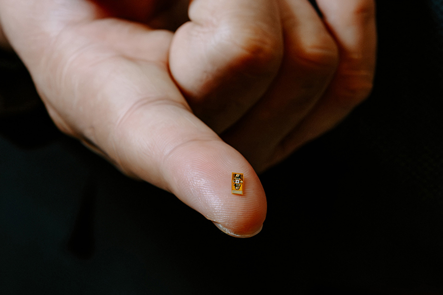 A small chip, meant to be implanted in the brain, sits on the fingertip of Professor Sen.