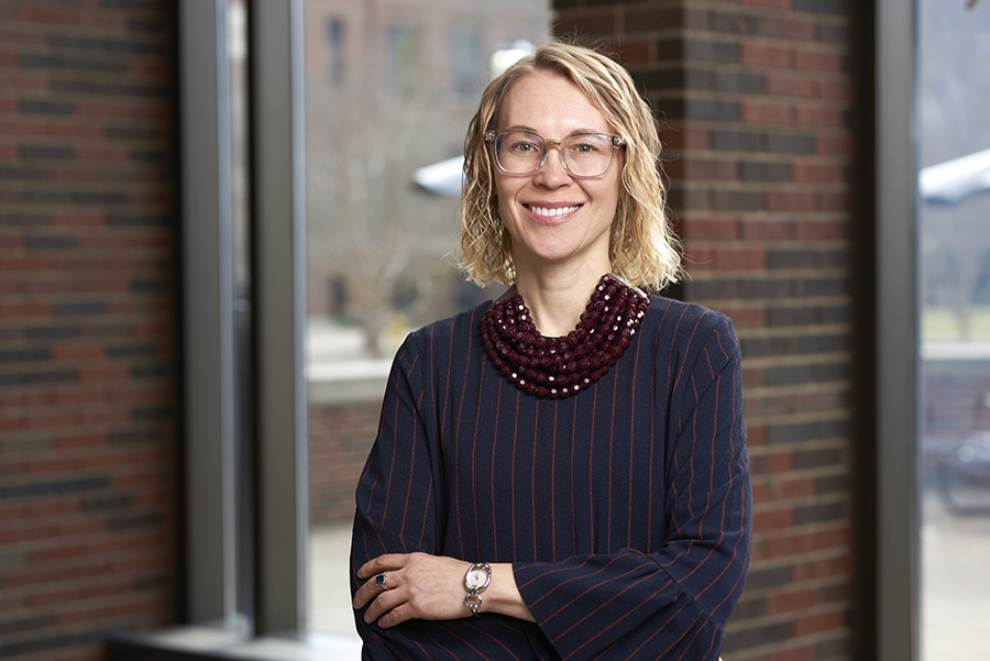 Professor Alexandra Boltasseva poses for a portrait. She is wearing glasses, a blue and white striped dress, and a red necklace.