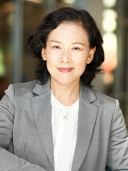 Haiyan Wang poses for a portrait in the atrium of MSEE. She is wearing a white blouse with a gray suit jacket.