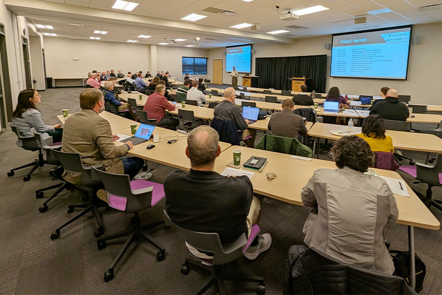 A large office environment where people are seated at desks, engaged with their laptops in a collaborative setting.