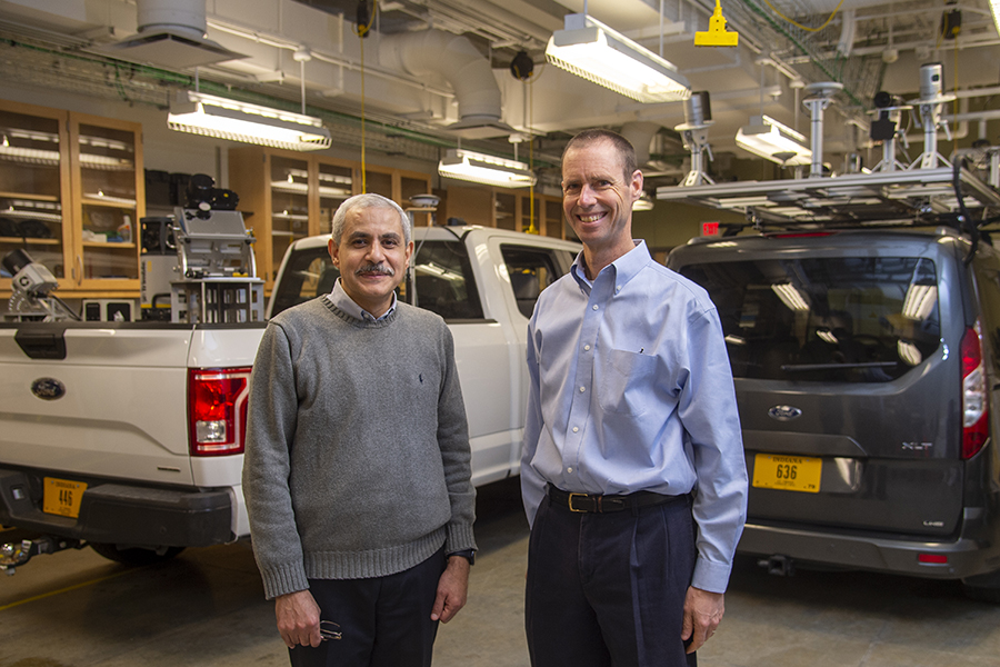Habib and Bullock posing in front of two vehicles