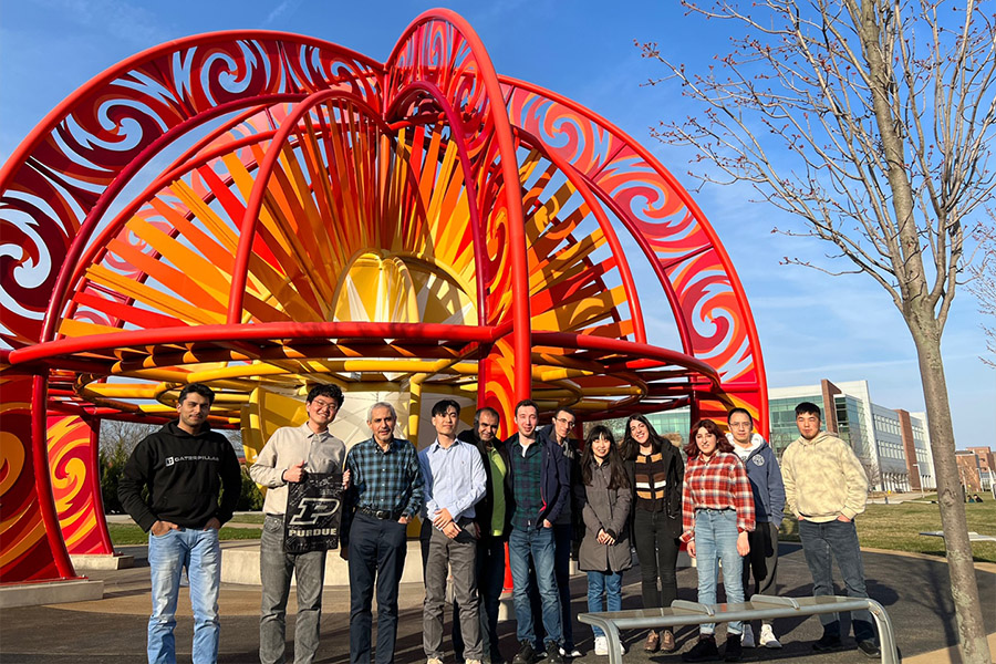 Group of people standing together in front of a circlular statue.