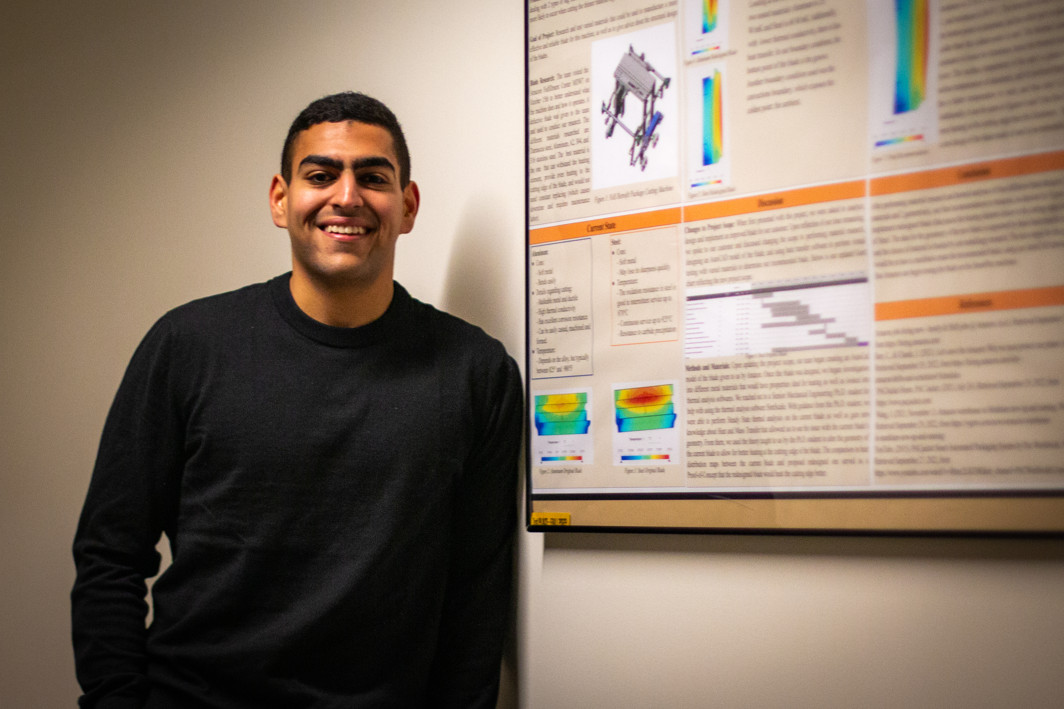 Saif posing next to his teams first place poster.