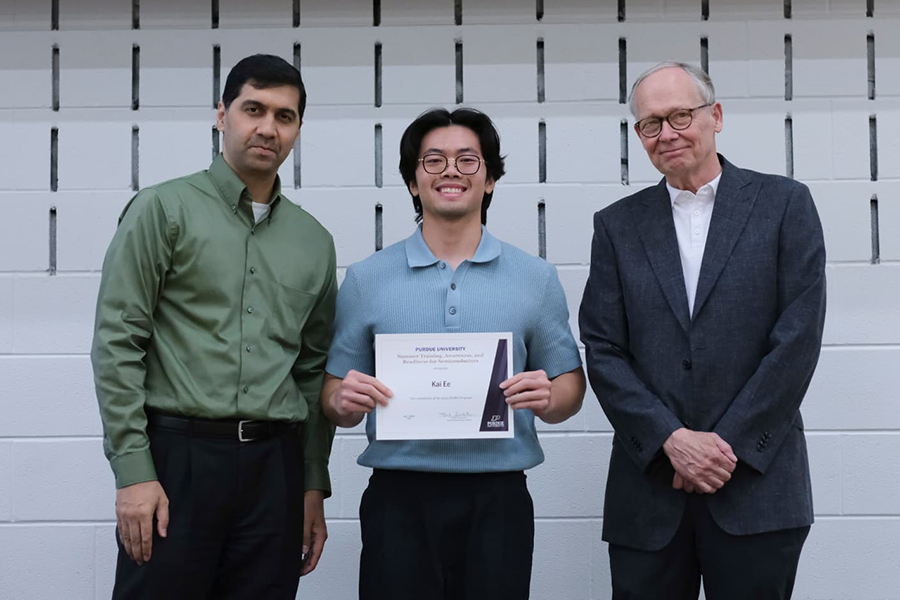 Three men standing next to each other, one holding a certificate
