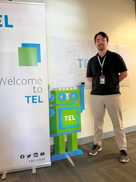 Janert standing in front of a banner that says "TEL"