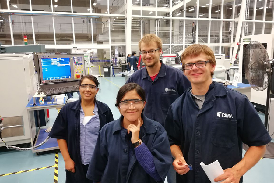 Students standing smiling in a factory
