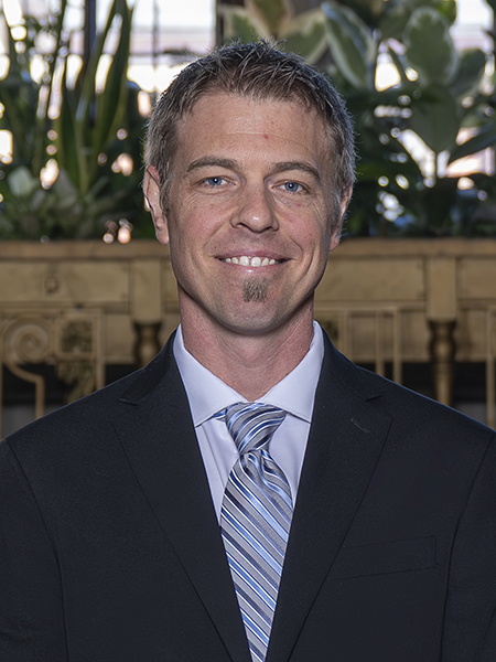 Man with short hair and blue eyes, smiling, wearing tie and jacket