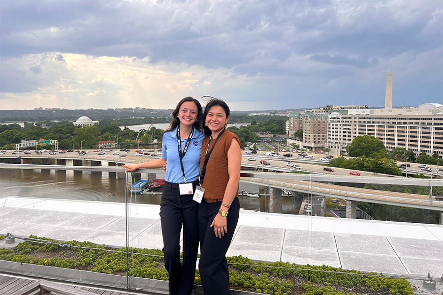 Two students (Morton left) smiling and standing on building rooftop.