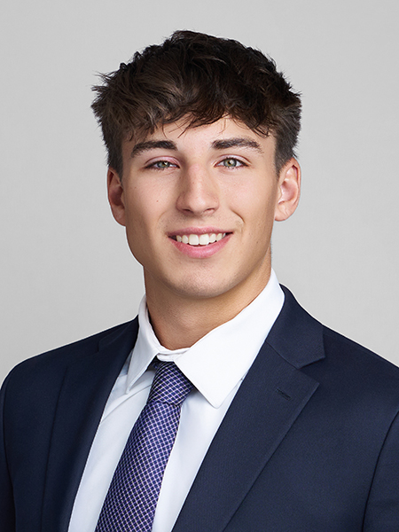 Mitch Davis, dark hair, light eyes, smiling, wearing dark suit with blue tie