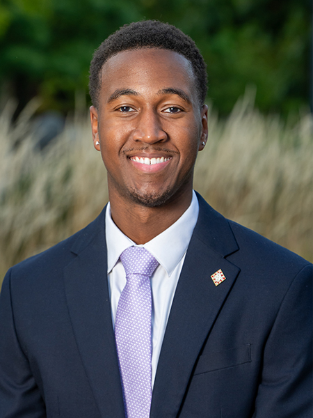 Student head shot, smiling, wearing a suit with a purple tie