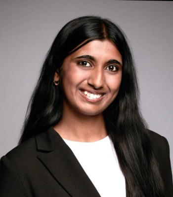 Student with black hair, dark eyes, smiling, wearing black blazer, head shot