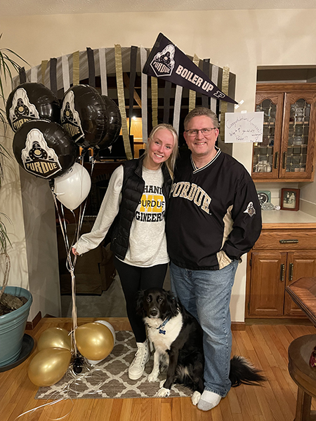 Father and daughter standing with Purdue pennants and balloons surrounding them